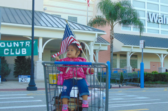 Little girl waiving the American Flag | The Joy of Giving supports families in need in Collier County