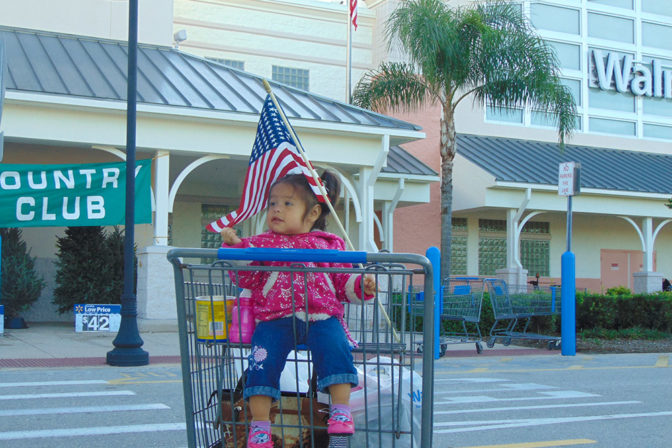 Little girl waiving the American Flag | The Joy of Giving supports families in need in Collier County